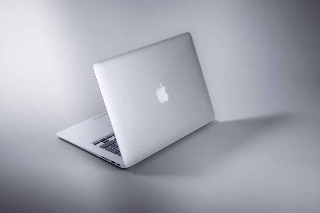 MacBook aberto sobre mesa de escritório minimalista com café e smartphone ao lado.